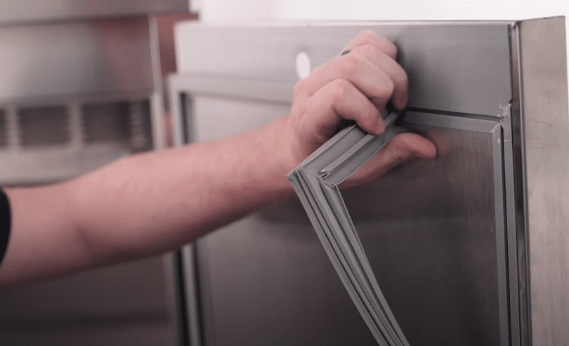 man is holding the door seal of refregerator