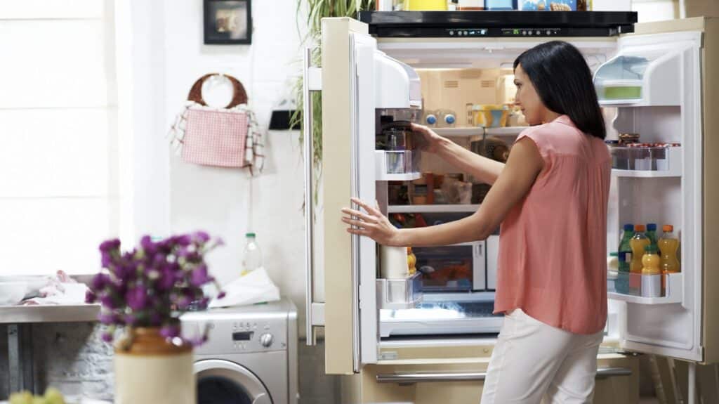 Woman looking in the fridge and taking some jar bottle