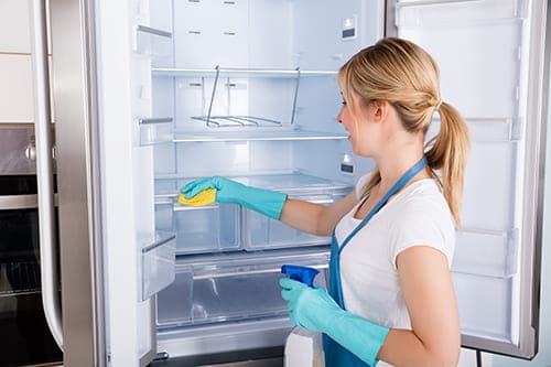 a lady cleaning the refrigerator from inside