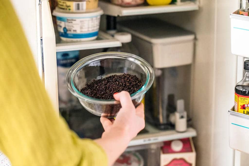 a lady holding coffee grounds bowl 