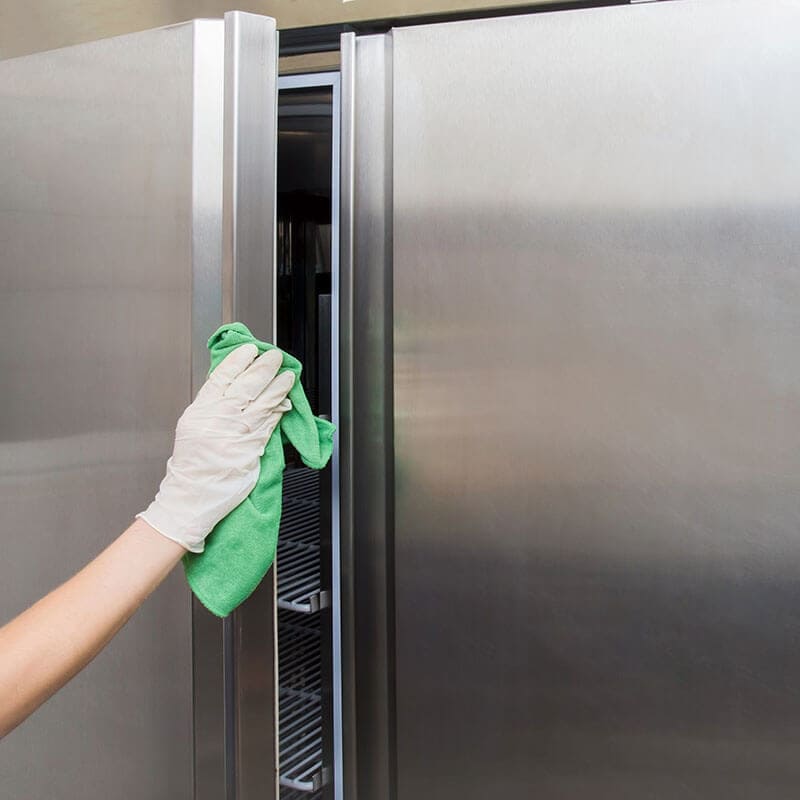 a man cleaning the fridge door with a cloth