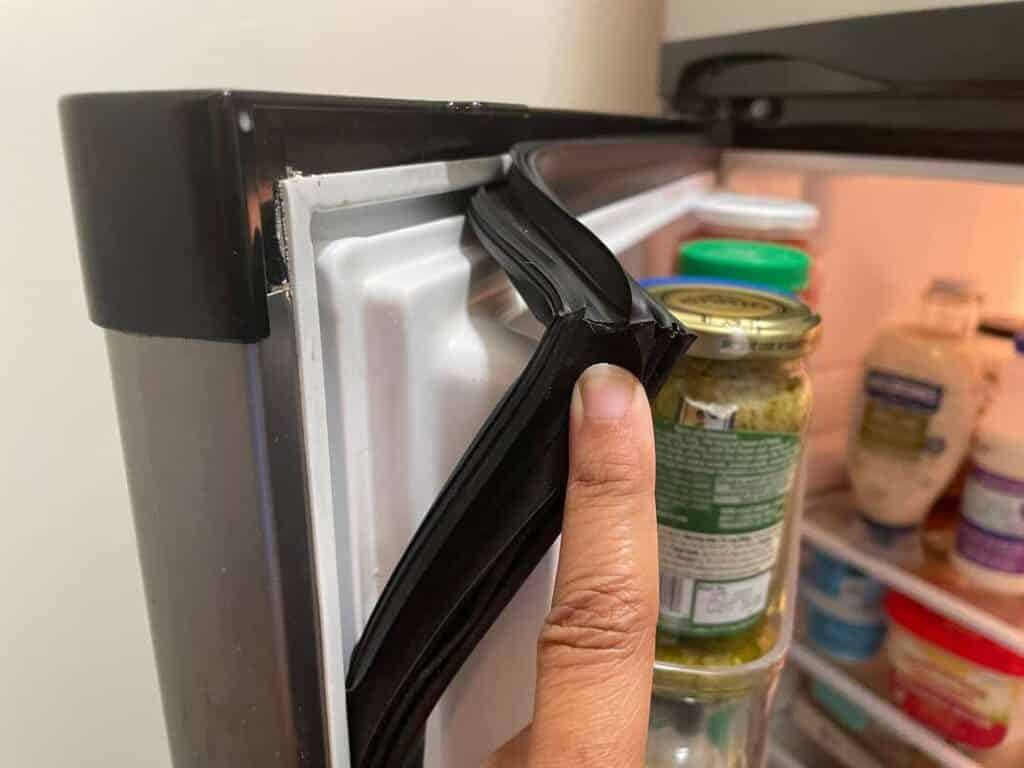 a person checking the fridge door seal