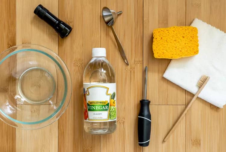 vinegar bottle, brush, sponge and a bowl and other  materials for refrigerator dispenser cleaning 