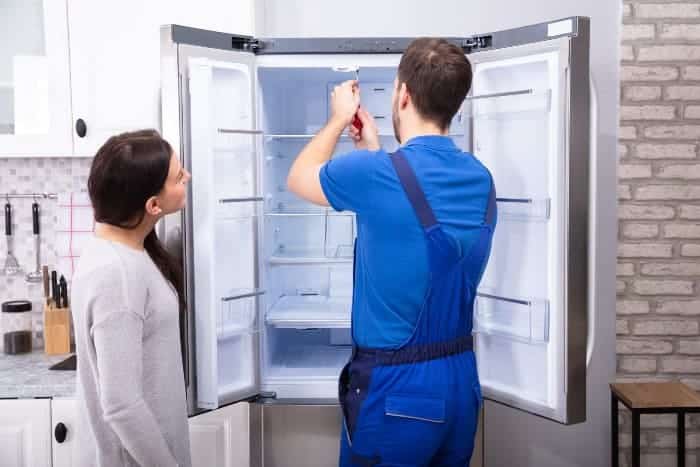 an expert examining the refrigerator for mantenance