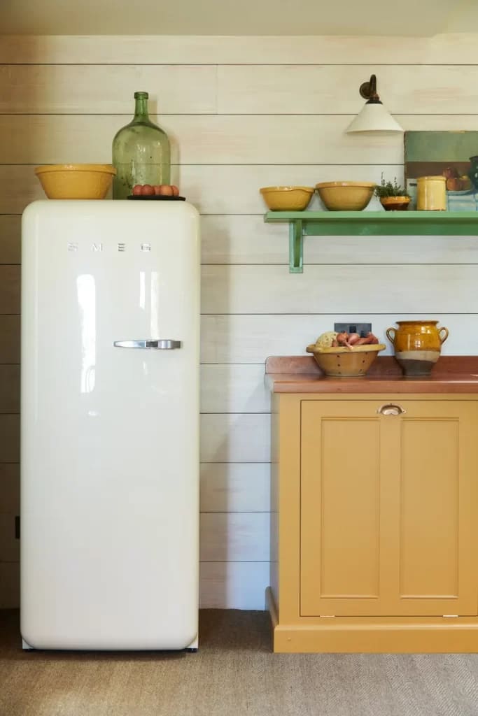 a single door refrigerator with bowls and jars placed on top for decoration