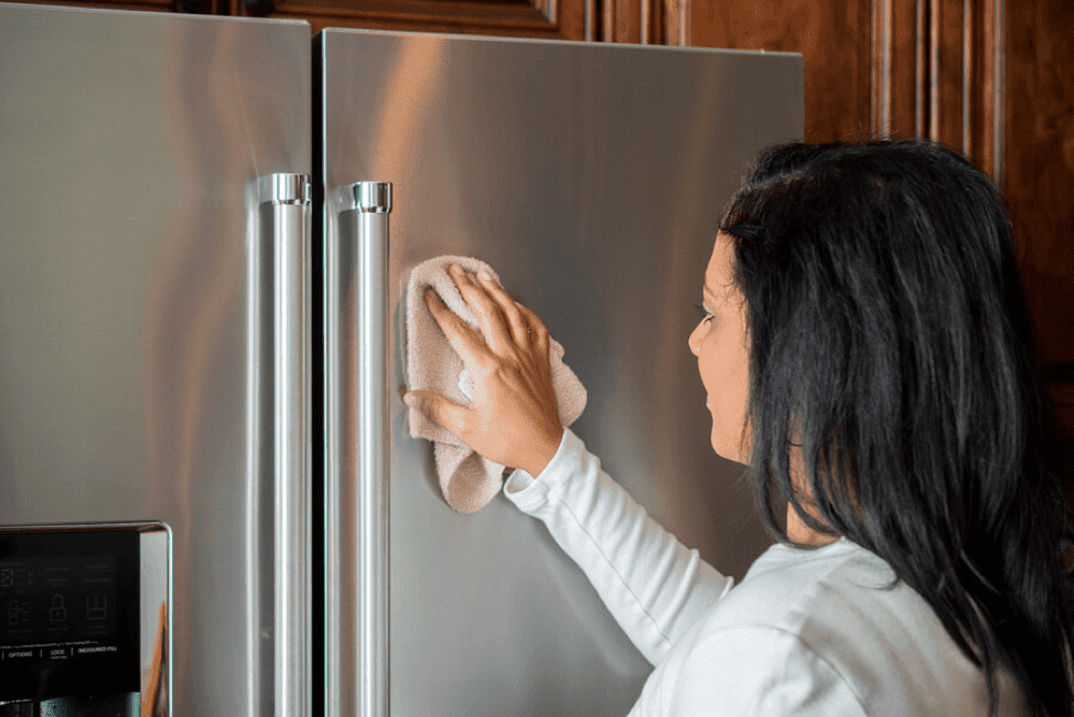 woman cleaning refrigerator doors with a microfiber cloth