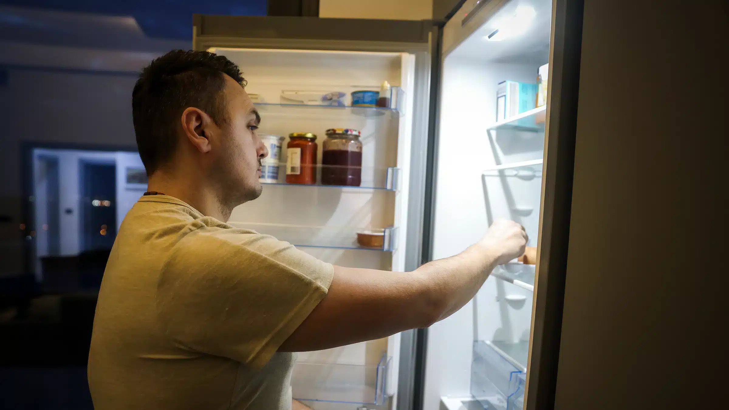 A side view of a guy with an opened fridge