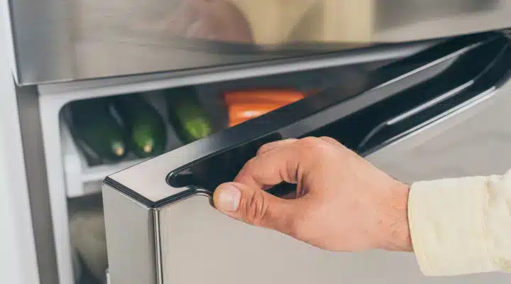 A view of a person s hand holding the fridge s handle