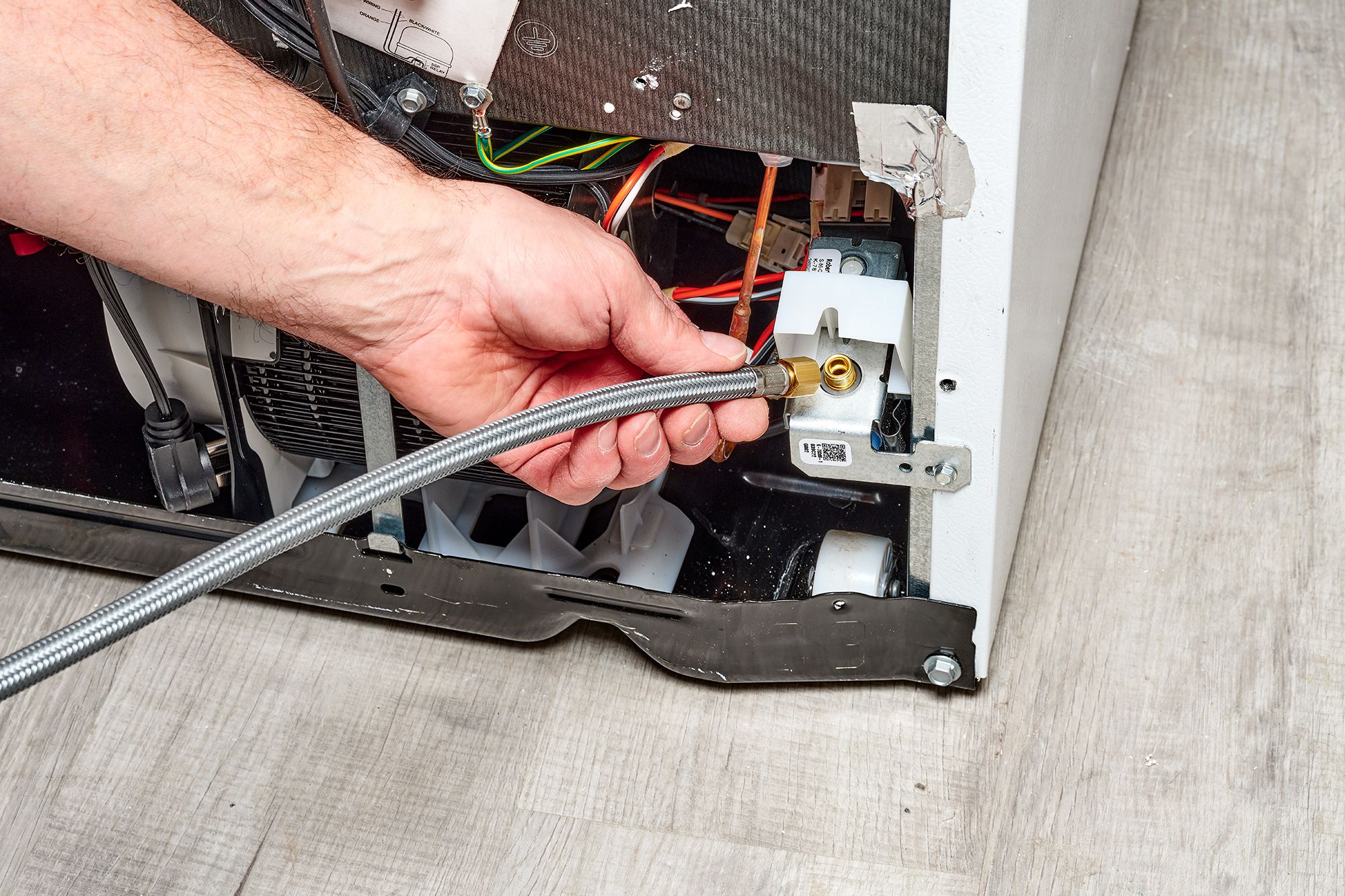 A view of a person checking the refrigerator water line