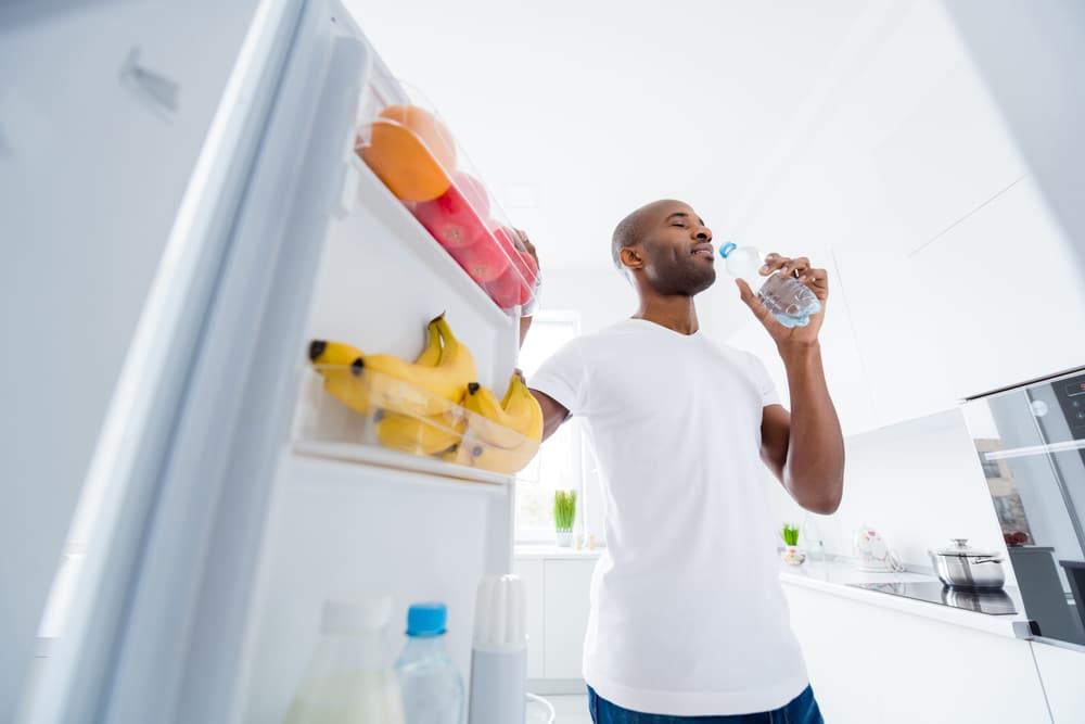 A view of a person drinking water from the fridge