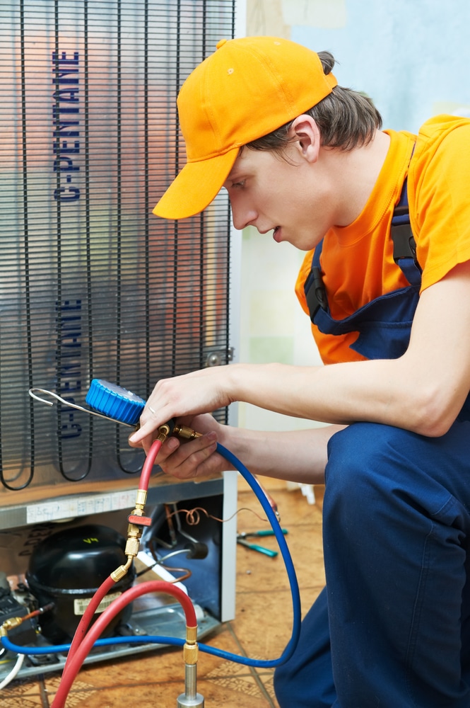 A view of a repairman checking the back of fridge