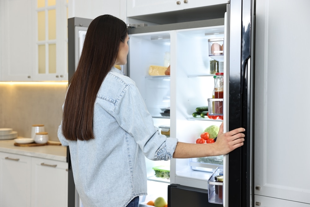 A back view of a girl standing with an open fridge