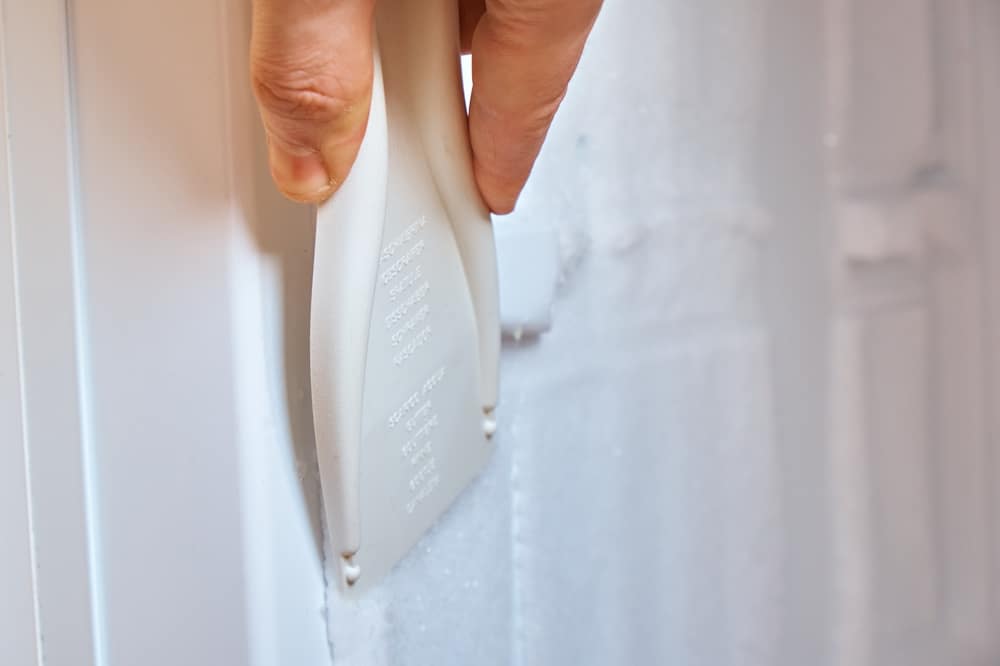 A view of a person scratching off frosting and ice from a freezer