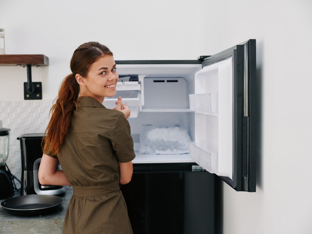 A view of a woman smiling and looking back with an open freezer